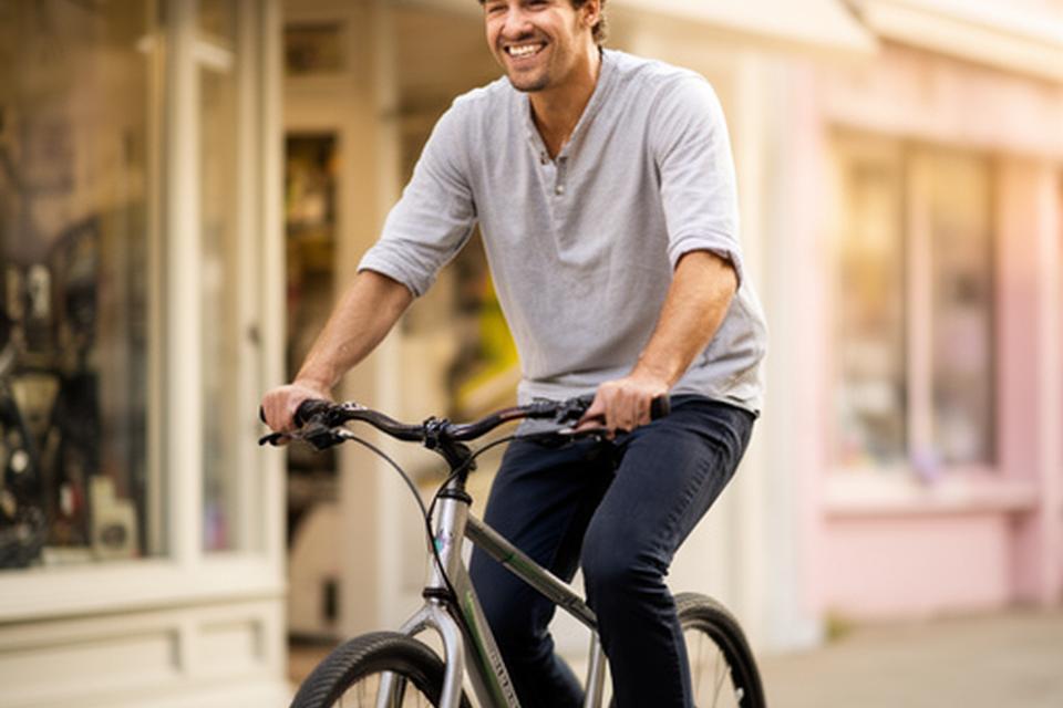 Cliente a testar uma bicicleta à saída da loja com expressão satisfeita